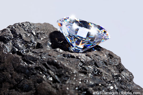 Nahaufnahme eines funkelnden geschliffenen Diamants, der auf einem dunklen Stein positioniert ist