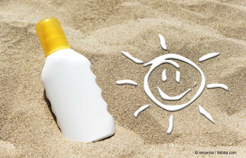 bottle of unlabelled sunscreen possitioned in the sand next to the drawing of a sun made from sunscreen as an application example for titanium dioxide particles © vimarovi / Fotolia.com