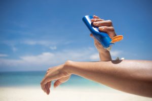 outstretched arm applying sunscreen, blue sky in background. Image source ©lesterman -stock.adobe.com